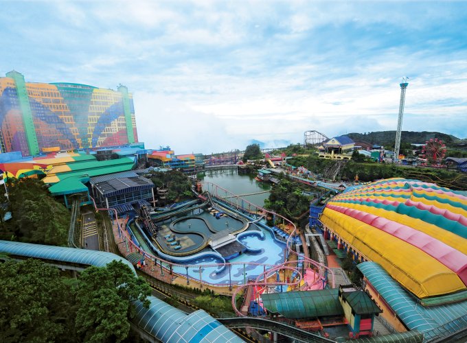 Tourists enjoying the scenic view from the Genting Highlands cable car ride, with lush green mountains and the skyline of Kuala Lumpur in the background, showcasing a perfect mix of nature and modern city life during a vacation in Malaysia