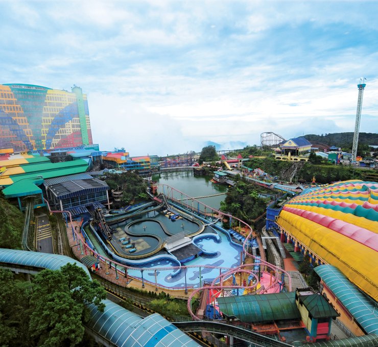 Tourists enjoying the scenic view from the Genting Highlands cable car ride, with lush green mountains and the skyline of Kuala Lumpur in the background, showcasing a perfect mix of nature and modern city life during a vacation in Malaysia