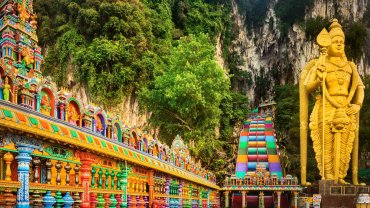 Golden Lord Murugan statue and colorful steps leading to Batu Caves temple in Malaysia